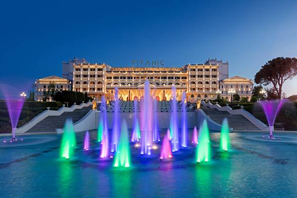 Beleuchtetes Titanic Mardan Palace Hotel mit Wasserfontaene im Vordergrund
