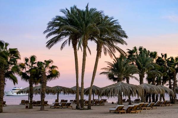 Serry Beach Resort Strand mit Palmen und Sonnenuntergang im Hintergrund.