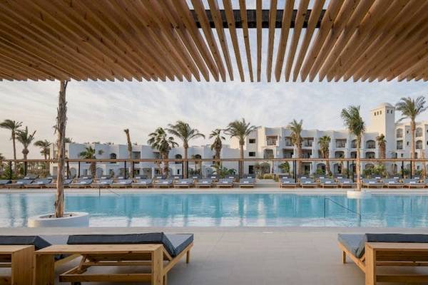 Außenpool des Serry Beach Resorts mit Holzliegen und Palmen im Hintergrund.