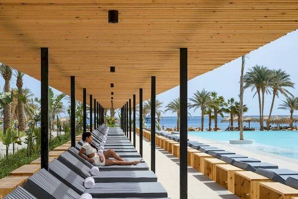 Ein Mann entspannt sich auf einer Liege in einem Loungebereich des Serry Beach Resorts.