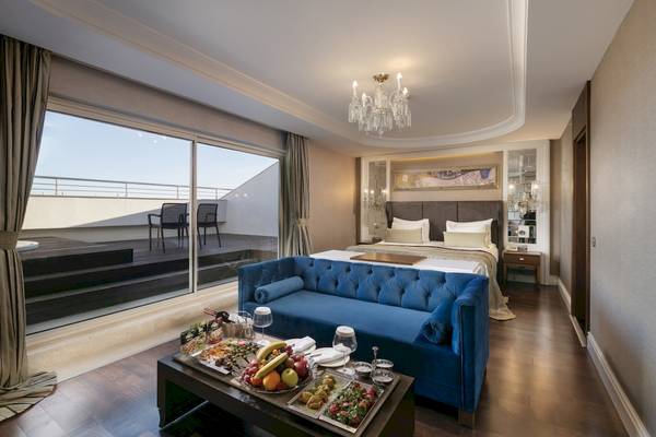 Innenansicht der Suite im Dobedan Exclusive Hotel & Spa Belek mit großem Bett, blauem Sofa und Balkon