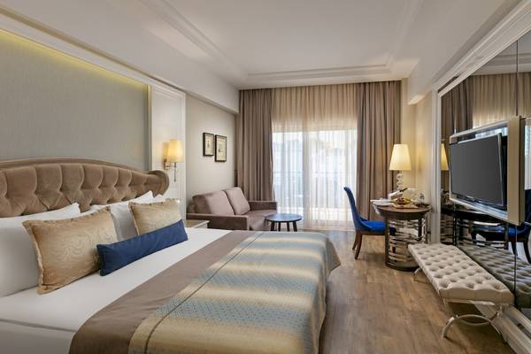 Schlafzimmer im Dobedan Exclusive Hotel & Spa Belek mit großem Bett, Sofa, Fernseher und Esstisch.