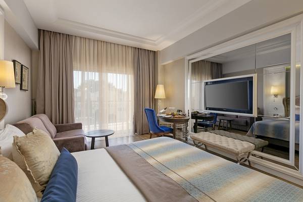Schlafzimmer im Dobedan Exclusive Hotel & Spa Belek mit großem Bett, Fernseher und Sofa.