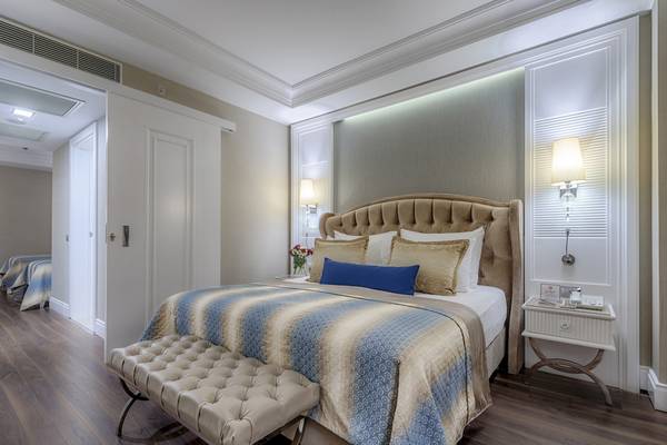Schlafzimmer-Innenansicht des Dobedan Exclusive Hotel & Spa Belek mit einem großen Bett, einem Nachttisch und dekorativen Lampen.