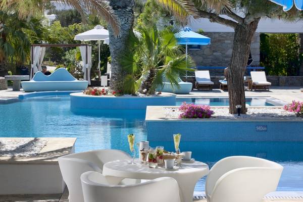 Pool-Loungebereich im Mykonos Theoxenia Boutique Hotel mit weißen Stühlen und Tischen.