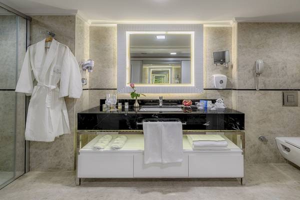 Badezimmer im Dobedan Exclusive Hotel & Spa Belek mit schwarzer Marmorplatte und weißen Möbeln.