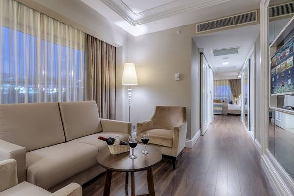 Wohnbereich des Dobedan Exclusive Hotel & Spa Belek mit Sofa, Tisch und Fernseher.