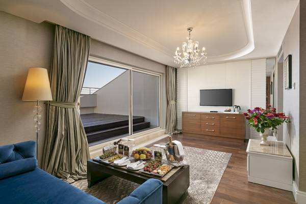 Innenansicht der Suite im Dobedan Exclusive Hotel & Spa Belek mit Wohnzimmer, Essbereich, Fernseher und Balkon.