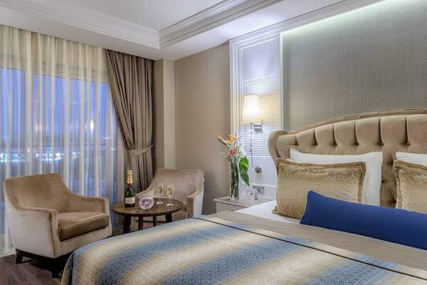 Luxuriöses Hotelschlafzimmer mit Bett, Sesseln und Champagnerflasche