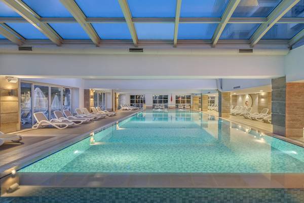 Innenpool im Dobedan Exclusive Hotel & Spa Belek mit weißen Liegestühlen und Glasdach