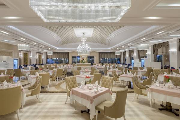 Innenansicht des Restaurants im Dobedan Exclusive Hotel & Spa Belek mit vielen gedeckten Tischen und Stühlen.