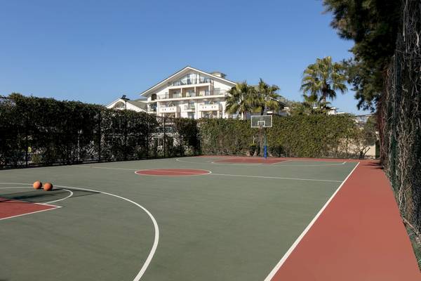 Basketballplatz vor dem Dobedan Exclusive Hotel & Spa Belek mit leerem Spielfeld und einer Villa im Hintergrund.
