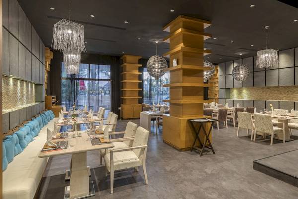 Innenraum des Dobedan Exclusive Hotel & Spa Belek mit Tischen und Stühlen, hängenden Lampen und gepolsterten Bänken.