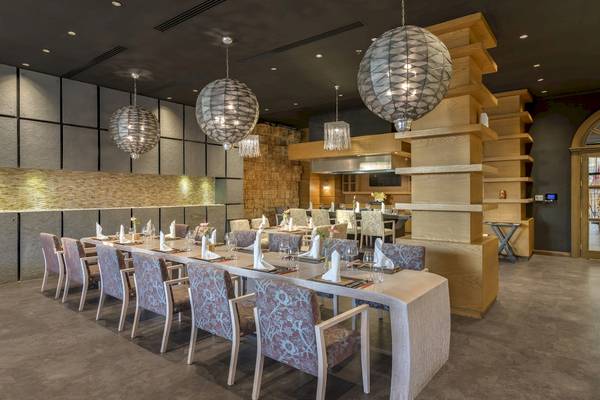 Interieur des Dobedan Exclusive Hotel & Spa Belek mit einem langen Esstisch, der von dekorativen Kronleuchtern beleuchtet wird.