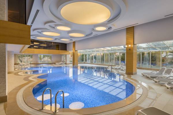 Innenpool im Dobedan Exclusive Hotel & Spa Belek mit Liegen und Glaswänden.