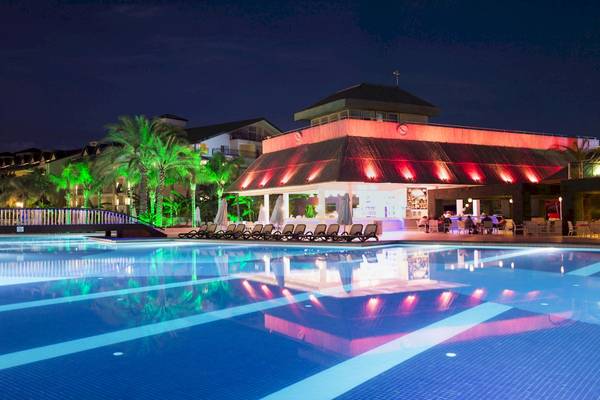 Pool im Dobedan Exclusive Hotel & Spa Belek bei Nacht mit beleuchteten Gebäuden und Palmen
