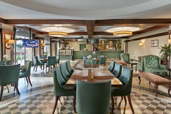 Innenraum des Cafes im Dobedan Exclusive Hotel & Spa Belek mit grünen Stühlen und Tischen