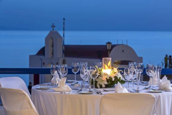 Abendessen auf einem Tisch im Außenbereich des Mykonos Theoxenia Boutique Hotels mit Blick auf eine Kirche und das Meer.