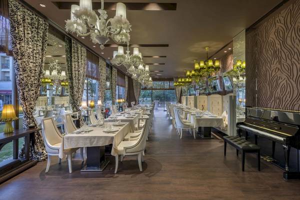 Restaurant im Dobedan Exclusive Hotel & Spa Belek mit weißen Tischen, Stühlen und Kronleuchtern.