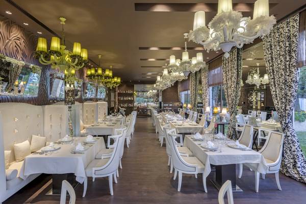 Restaurant des Dobedan Exclusive Hotel & Spa Belek mit weißen Möbeln und hängenden Kronleuchtern.