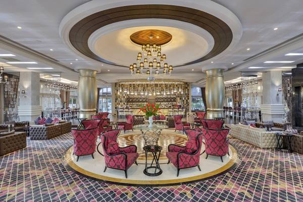 Lobby des Dobedan Exclusive Hotel & Spa Belek mit roten Stühlen und zentralem Tisch.