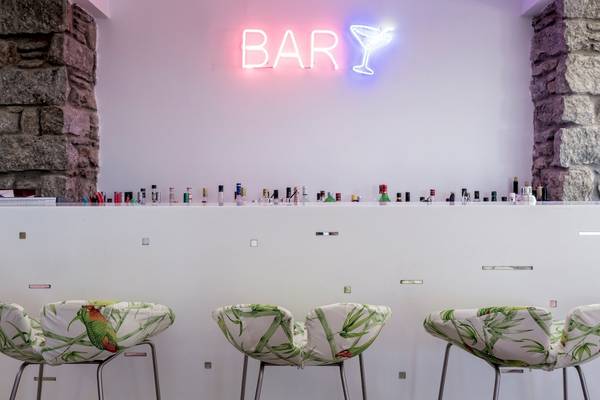 Die Bar im Mykonos Theoxenia Boutique Hotel mit einem rosa und blauen Neonschild.