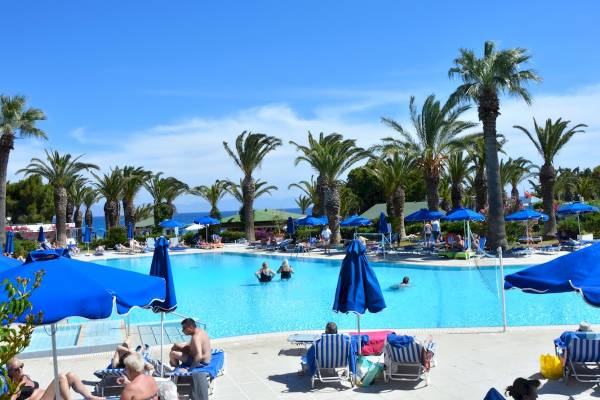 Hotel Blue Horizon Poolbereich mit vielen Gästen, blauen Sonnenschirmen und Palmen
