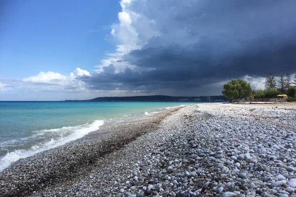 Ein Strand mit Kieseln und einem dunklen Himmel im Hintergrund, kurz vor einem Gewitter.