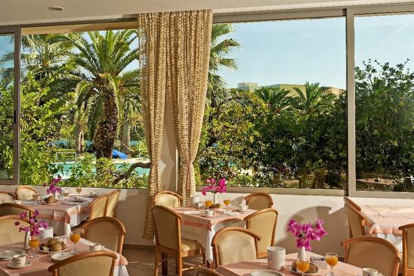 Frühstücksraum im Blue Horizon Hotel mit Blick auf einen Swimmingpool und Palmen