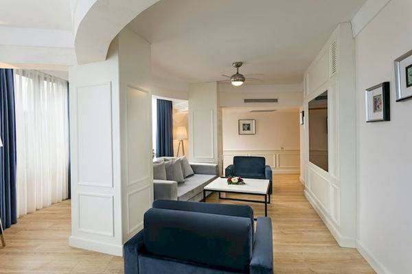 Hotellounge Bereich mit Sofa, Tisch, Lampen und blauen Vorhängen.