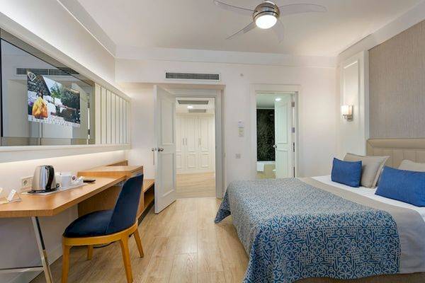 Innenansicht eines Hotelzimmers im Limak Atlantis Deluxe Hotel & Resort mit Bett, Schreibtisch und Fernseher.