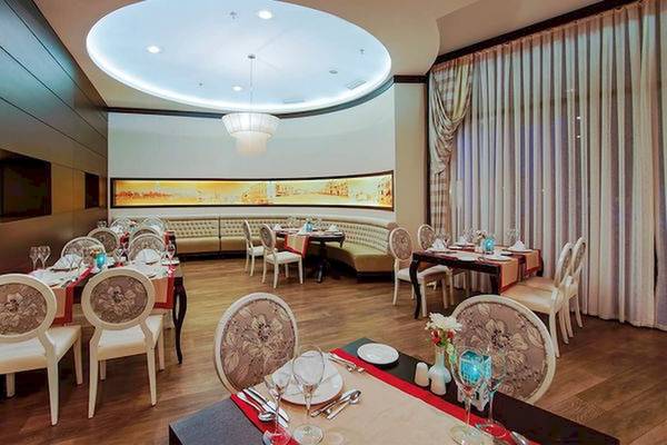 Innenansicht des Restaurants im Limak Atlantis Deluxe Hotel & Resort mit gepolsterten Bänken und runden Tischen.
