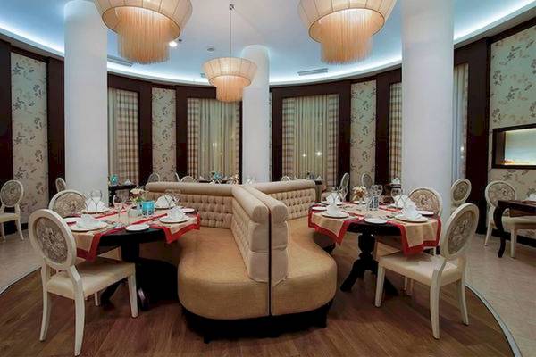 Innenbereich eines Restaurants im Limak Atlantis Deluxe Hotel & Resort mit runden Tischen und gepolsterten Eckbänken.