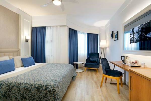 Ein modernes Hotelzimmer mit einem großen Bett, blauen Vorhängen und einem Schreibtisch.