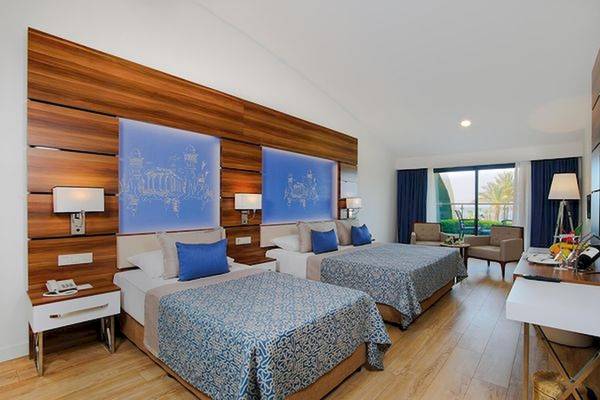 Doppelzimmer im Limak Atlantis Deluxe Hotel & Resort mit zwei Betten, Holzwänden und modernen Möbeln.