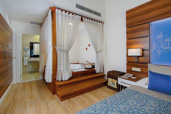 Hotelsuite mit Badewanne, Bett und Holzelementen im Innenraum.