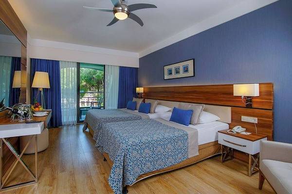 Ein modernes Hotelzimmer mit zwei Betten, blauen Vorhängen und einer Klimaanlage.