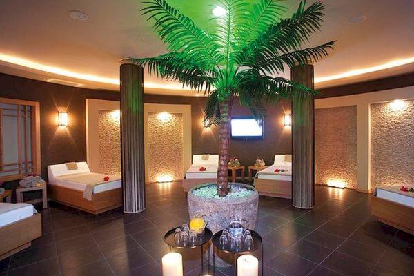 Innenansicht einer Suite im Limak Atlantis Deluxe Hotel & Resort mit Betten, einer Palme und einer Fernsehwand.
