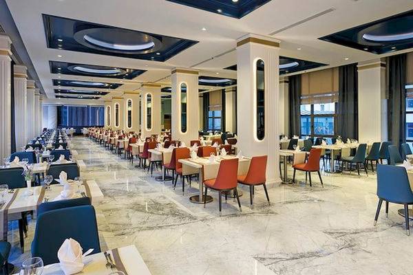 Innenansicht des Restaurants im Limak Atlantis Deluxe Hotel & Resort mit vielen gedeckten Tischen und Stühlen.