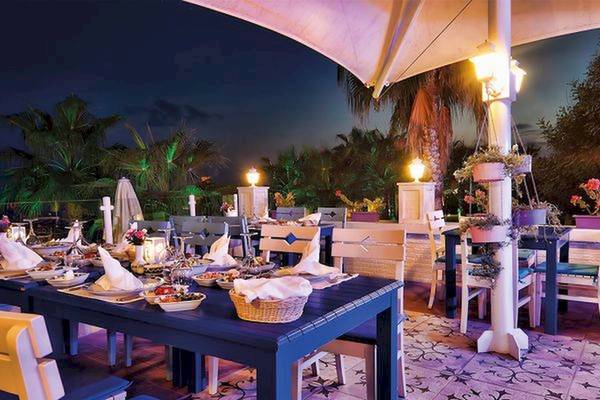 Hotel Terrasse bei Nacht mit vielen Tischdecken und Speisen.