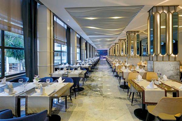 Innenansicht des Restaurants im Limak Atlantis Deluxe Hotel & Resort mit gedeckten Tischen und modernem Interieur.