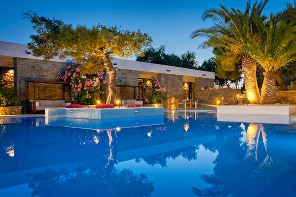 Poolbereich des Mykonos Theoxenia Boutique Hotels mit Steinmauer, Blumen und Palmen