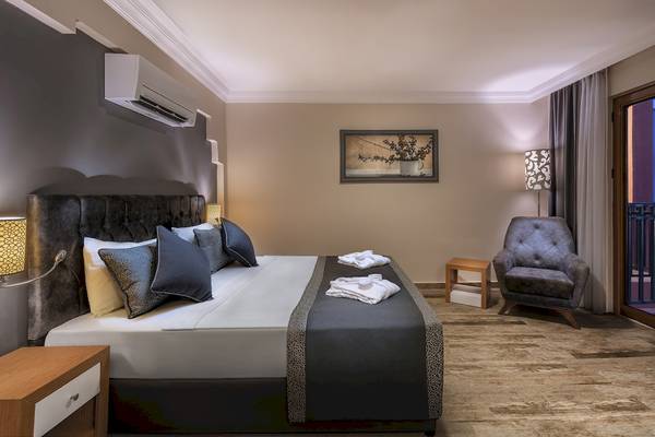 Schlafzimmer im VONRESORT Golden Beach Hotel mit Bett, Sesseln und Blick auf Terrasse.