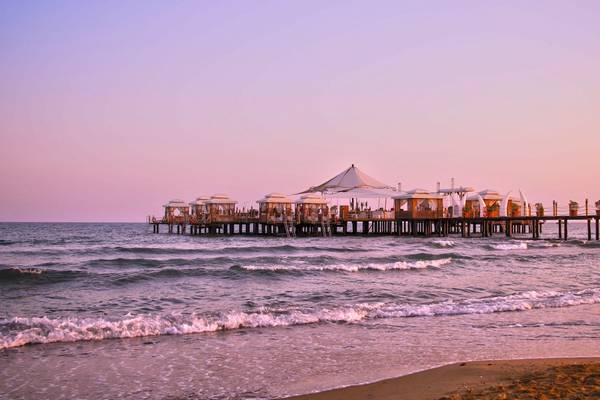 Vonresort Golden Beach Pier bei Sonnenuntergang mit rosa Himmel und Wellen am Strand