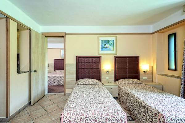 Doppelzimmer im VONRESORT Golden Beach mit zwei Betten, Nachttischen, Lampen und einem offenen Badezimmer.
