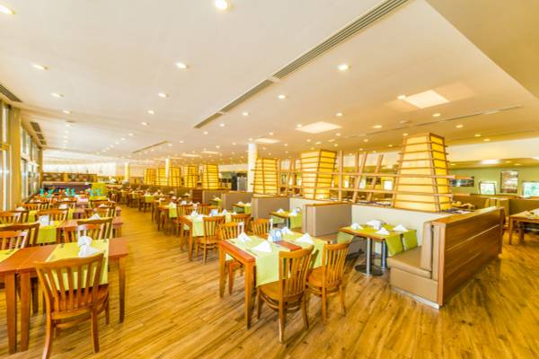 Innenansicht des Restaurants im VONRESORT Golden Beach mit gelben Tischen und Holzbänken.
