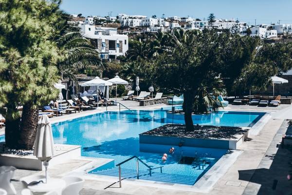 Pool des Mykonos Theoxenia Boutique Hotels mit weißen Liegestühlen und Palmen