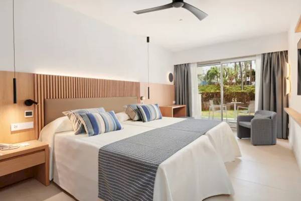 Innenansicht eines Hotelzimmers im Hipotels Mediterraneo, mit Doppelbett, Wohnzimmerbereich und Gartenaussicht.