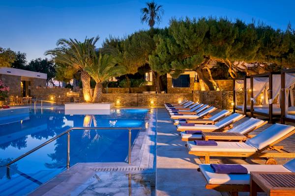 Der Außenpool des Mykonos Theoxenia Boutique Hotels bei Nacht mit Sonnenliegen und Palmen