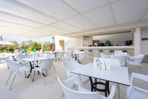 Terrasse des Hipotels Mediterraneo mit weißen Tischen und Stühlen unter einem weißen Sonnendach.